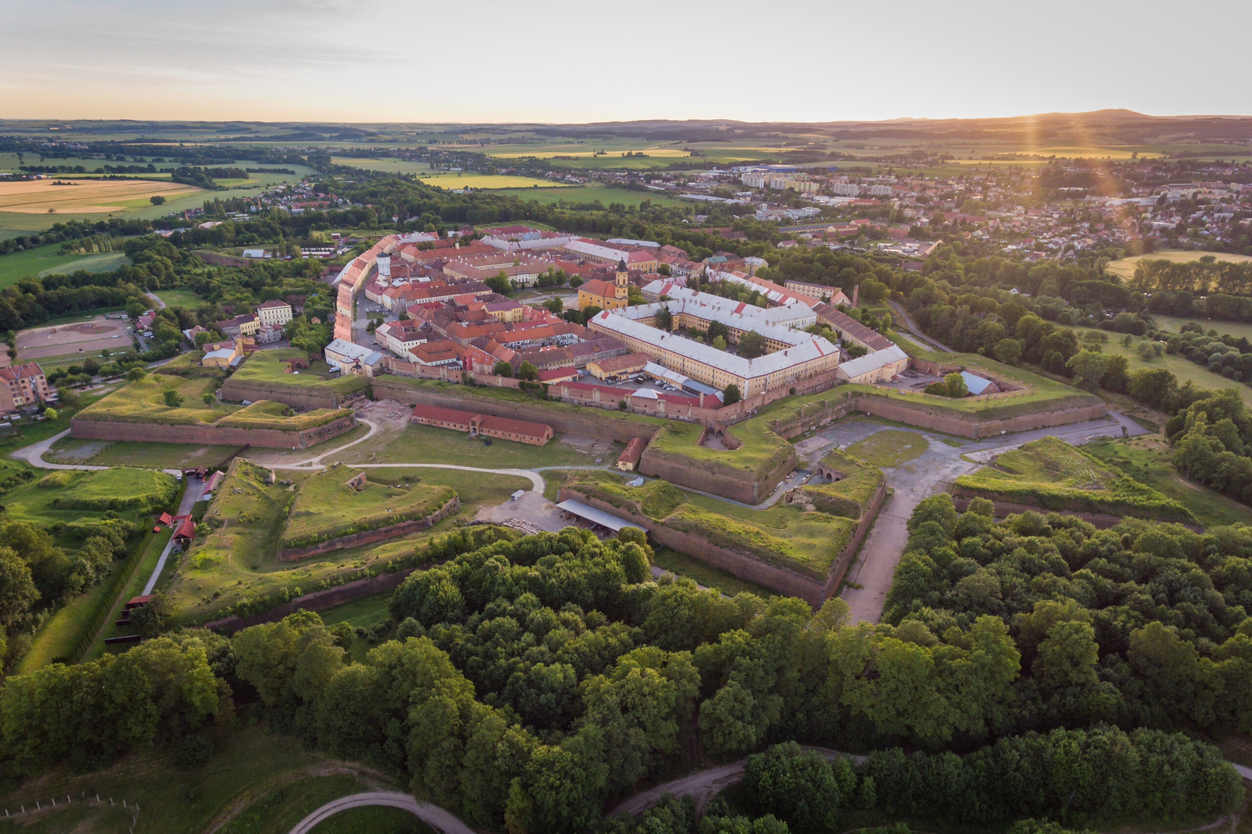 Letecký pohled na Pevnost Josefov při západu slunce. Kromě pevnosti je všude plno zeleně.